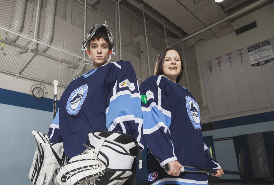 deux élèves, une fille et un garçon en habit de hockey