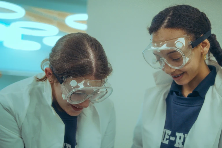 Deux élèves dans un laboratoire de sciences avec leurs lunettes de protection, souriantes